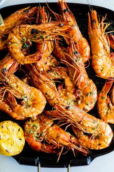 grilled shrimp with lemon wedges and parsley on a black grilling pan