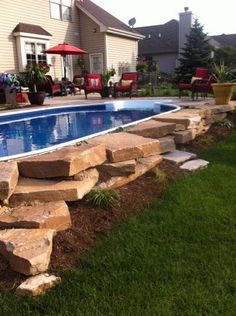 a backyard with a swimming pool and stone steps leading up to the side of it