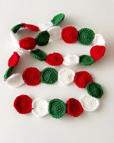 crocheted christmas garland with red, white and green ornaments on top of it