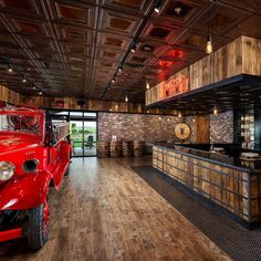 a red truck is parked in the middle of a room with wood floors and exposed ceilings