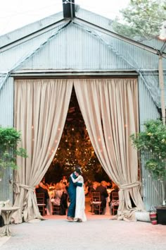 a bride and groom standing in front of an open barn door at their wedding reception