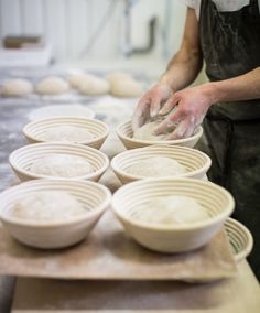 a man in an apron is kneading dough into bowls