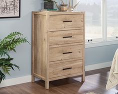 a wooden chest of drawers sitting on top of a hard wood floor next to a window