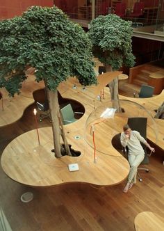 a woman sitting in an office chair next to a tree on top of a hard wood floor