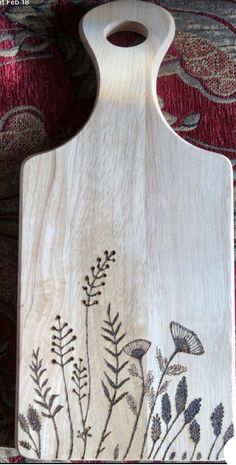 a wooden cutting board with an image of flowers on the front and side of it