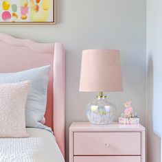 a pink bed with two nightstands next to it and a painting on the wall