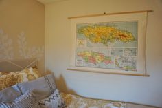 a map hanging on the wall above a bed in a room with pillows and blankets