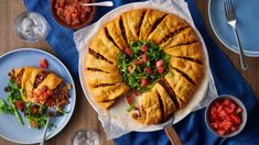 a table topped with lots of food and plates filled with different types of food on top of blue napkins