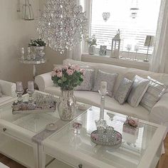 a living room filled with furniture and a chandelier hanging from the ceiling in front of a window