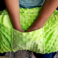 a person is holding a green object in their hands and it looks like they are making something out of fabric