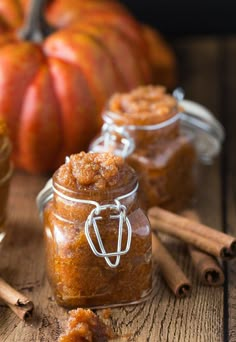 small jars filled with cinnamon sugar sitting on top of a wooden table next to pumpkins