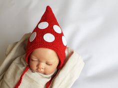 a baby wearing a red hat with white polka dots on it's head is sleeping