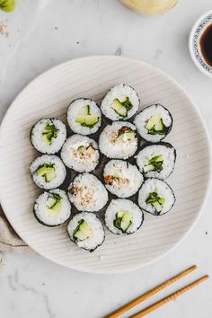 sushi on a plate with chopsticks next to it and a cup of coffee