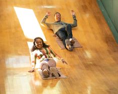 two people laying on the floor with their hands in the air