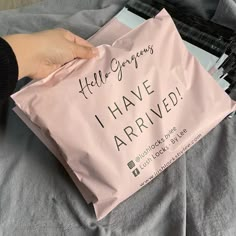 a person holding a pink bag with writing on it that says hello gorgeous i have arrived