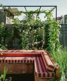 an outdoor hot tub in the middle of a garden surrounded by tall grass and plants