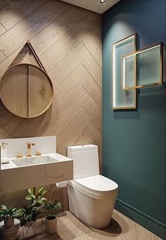 a bathroom with a toilet, sink and mirror in the wall next to potted plants