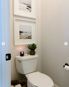 a white toilet sitting in a bathroom next to a wall mounted art above it's tank