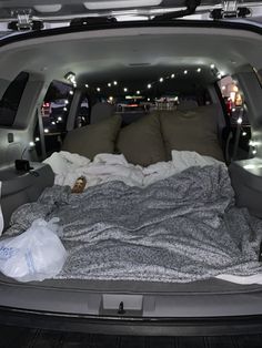 an open trunk with blankets and pillows in it