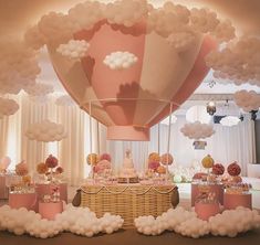 a large balloon filled with lots of white clouds floating over a table covered in cake