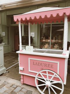 a pink and white ice cream cart sitting in front of a building