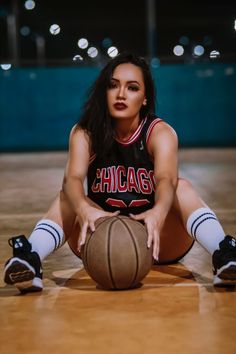 a woman sitting on the floor with a basketball