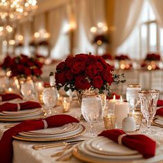 the table is set with red roses and gold place settings for dinner or wedding reception