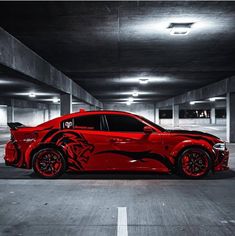 a red car parked in a parking garage with black and white designs on the side