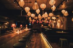 a dimly lit bar with lots of lights hanging from the ceiling and stools in front of it