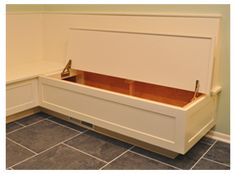 a white bench sitting in the corner of a room with tile flooring and walls