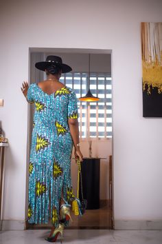 A woman posing in a blue and green African Print maxi dress with frills. Blue Ruffled Floor-length Maxi Dress, Blue Floor-length Ruffled Maxi Dress, Blue Floor-length Maxi Dress With Ruffles, Blue Bohemian Long Dress, Blue Fitted Long Sleeve Maxi Dress, Casual Ruffled Floor-length Maxi Dress, Blue Floor-length Maxi Dress For Summer, Casual Floor-length Ruffled Maxi Dress, Casual Floor-length Maxi Dress With Ruffles