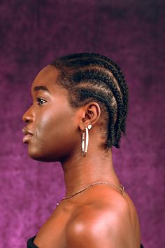 a woman with cornrows and earrings on her head looking off to the side