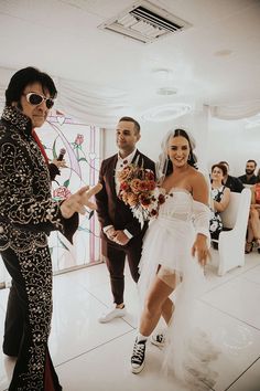 a bride and groom are walking down the aisle with their guests in the back ground