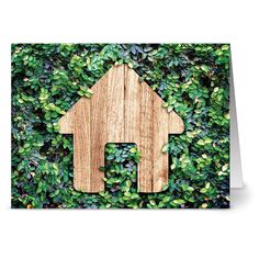 a wooden house surrounded by green leaves on top of a greeting card with an envelope