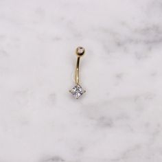 a gold nose piercing with a single diamond on the end, sitting on a marble surface