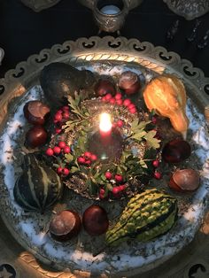 a lit candle is surrounded by fruits and vegetables on a platter with lace doily