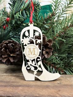 a christmas ornament hanging from a tree with pine cones and evergreen branches in the background