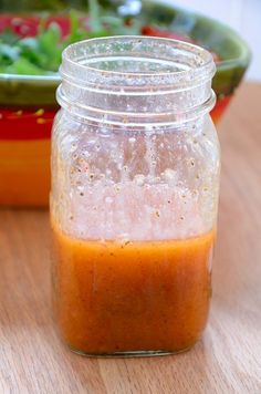 a jar filled with sauce sitting on top of a wooden table