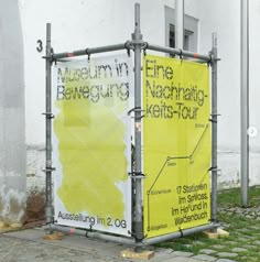 a yellow sign sitting on the side of a road next to a white and gray building