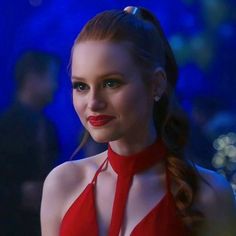 a woman wearing a red halter top and braid in front of a blue background