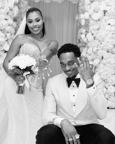 a bride and groom pose for a photo in front of a flower wall at their wedding