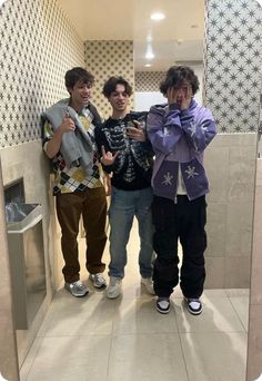 three young men standing in front of a mirror