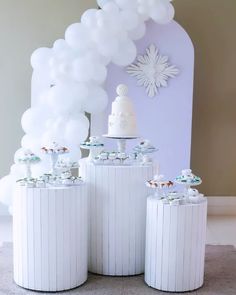 a table topped with white cakes and balloons