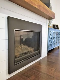 a fire place in the middle of a room with wood flooring and white walls