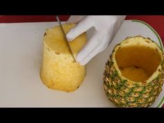 a person cutting up a pineapple on top of a white plate