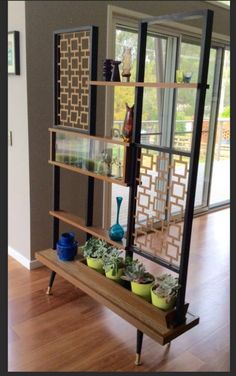 a shelf filled with pots and plants on top of a hard wood floor