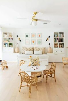 a living room filled with furniture and a white dining table surrounded by wooden chairs on top of hard wood flooring