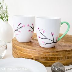 two coffee mugs sitting on top of a wooden tray next to a glass bowl