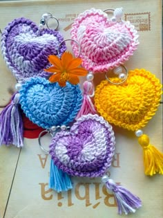 four crocheted heart keychains with tassels and flowers on them