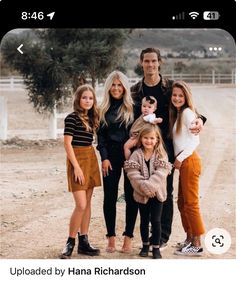 the family is posing for a selfie in front of a fence and dirt road